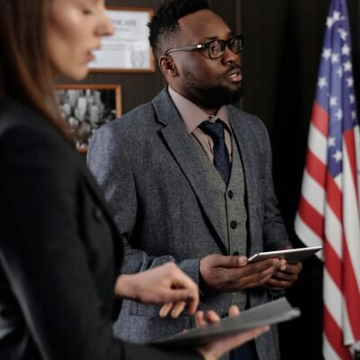 Business professionals discussing in an office with American flag backdrop, conveying a diplomatic setting.